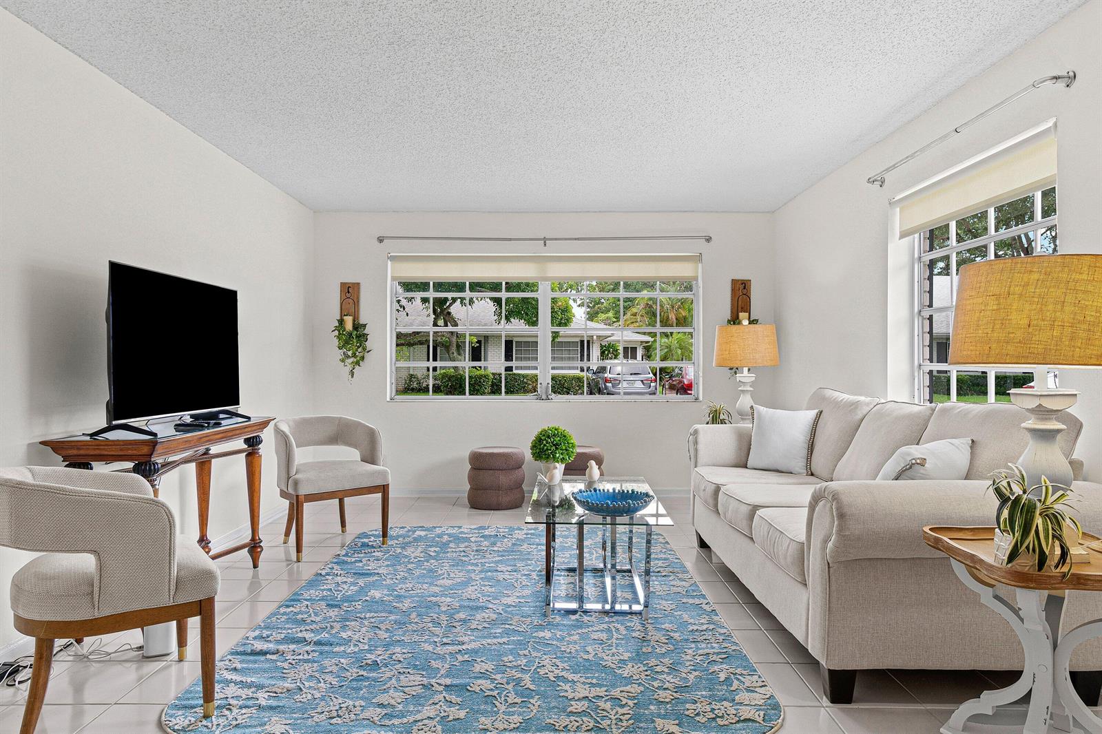 A living room features a blue patterned rug, a beige sofa, and a large window — 10098 S 40th Drive S, Boynton Beach FL 33436, BOYNTON BEACH, FL