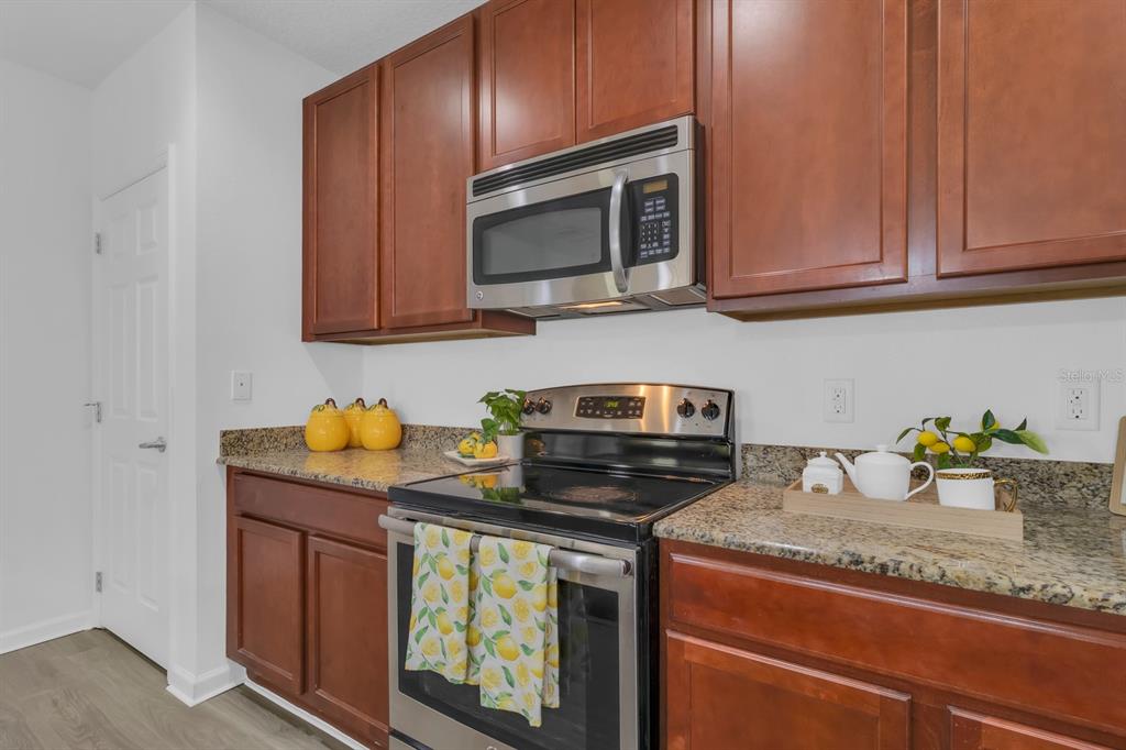 A kitchen features dark wood cabinets, granite countertops, and stainless steel appliances — 2943 CASABELLA DRIVE, KISSIMMEE, FL