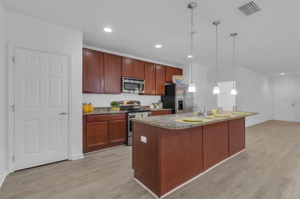 A kitchen with dark wood cabinets, granite countertops, a center island, and stainless steel appliances — 2943 CASABELLA DRIVE, KISSIMMEE, FL