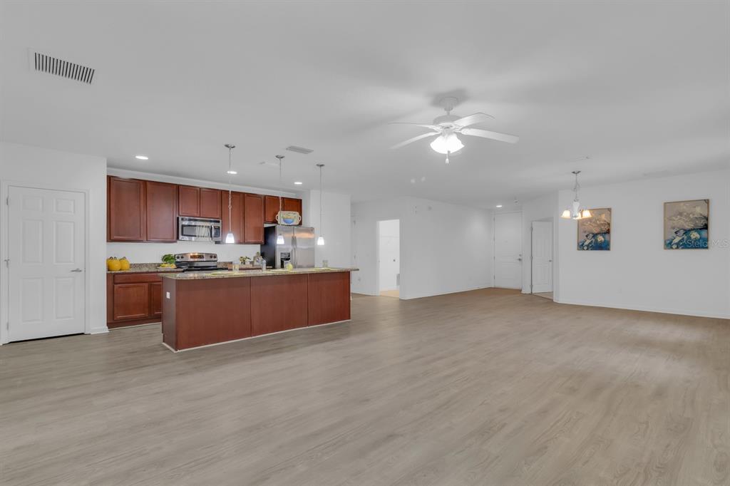 A kitchen with dark wood cabinets and a center island opens into a large living area — 2943 CASABELLA DRIVE, KISSIMMEE, FL