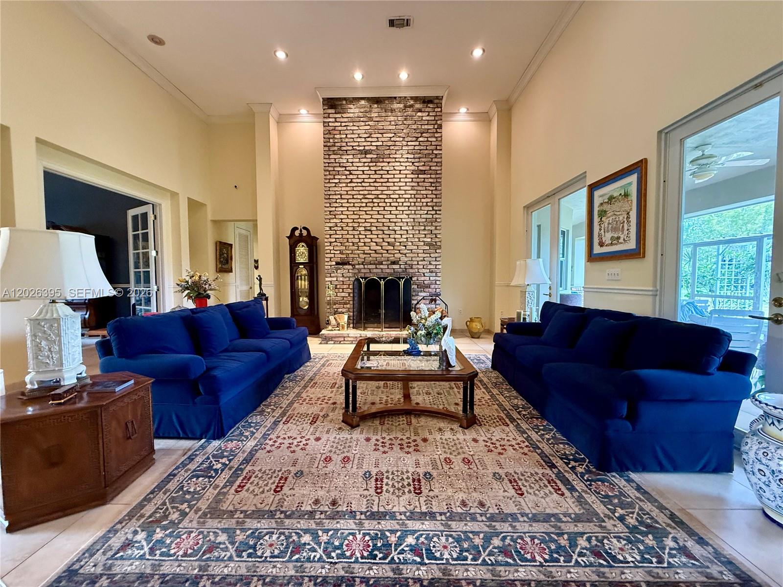 A living room features two blue sofas, a brick fireplace, and a large patterned rug — HOMESTEAD, FL