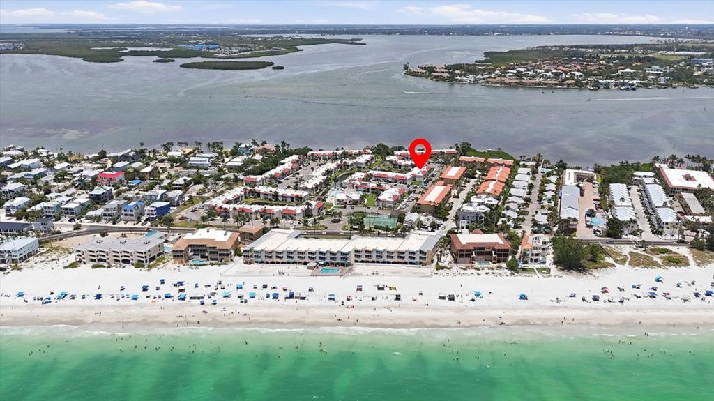 An aerial view shows a beachfront resort complex with multiple buildings, pools, and sandy shores — 1801 GULF DRIVE N UNIT 277, BRADENTON BEACH, FL