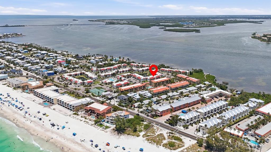 An aerial view shows a coastal condominium complex near a beach and bay — 1801 GULF DRIVE N UNIT 277, BRADENTON BEACH, FL