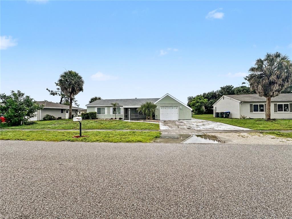 A single-story house with a green exterior, a white garage door, and a paved driveway — 3078 GREENDALE ROAD, NORTH PORT, FL
