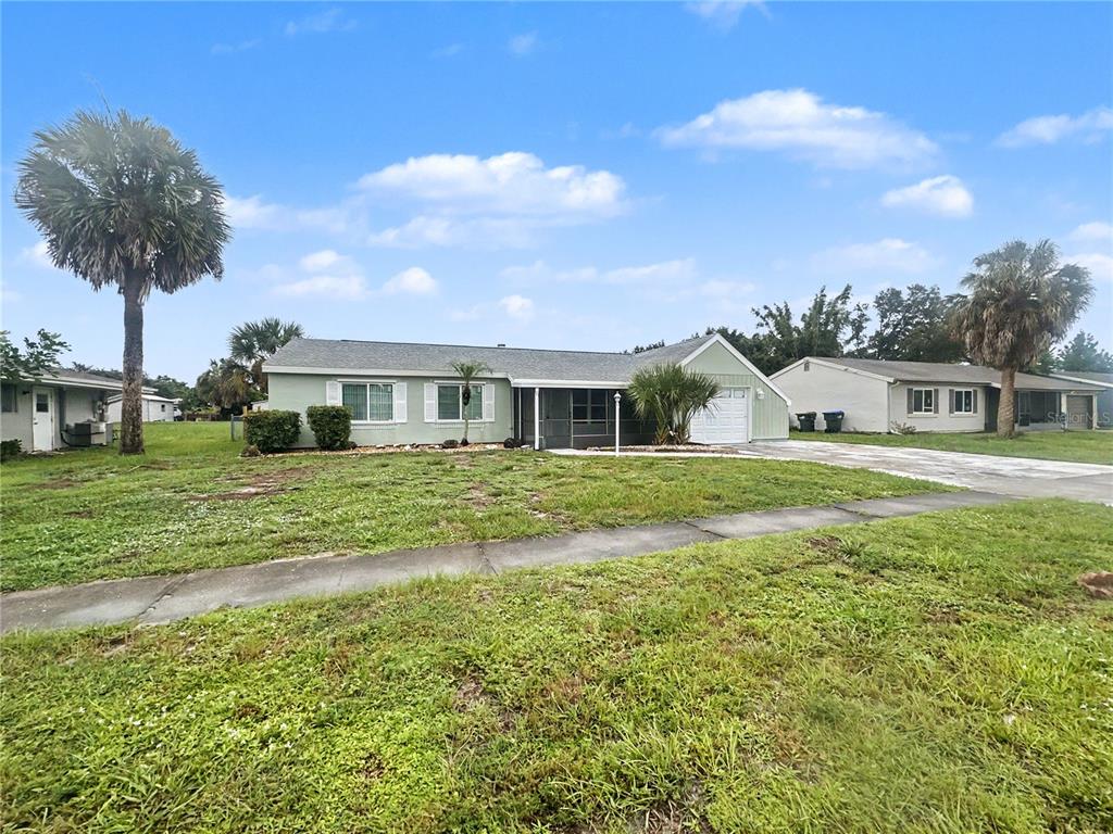 A single-story house with a light green exterior, a front porch, and a paved driveway — 3078 GREENDALE ROAD, NORTH PORT, FL