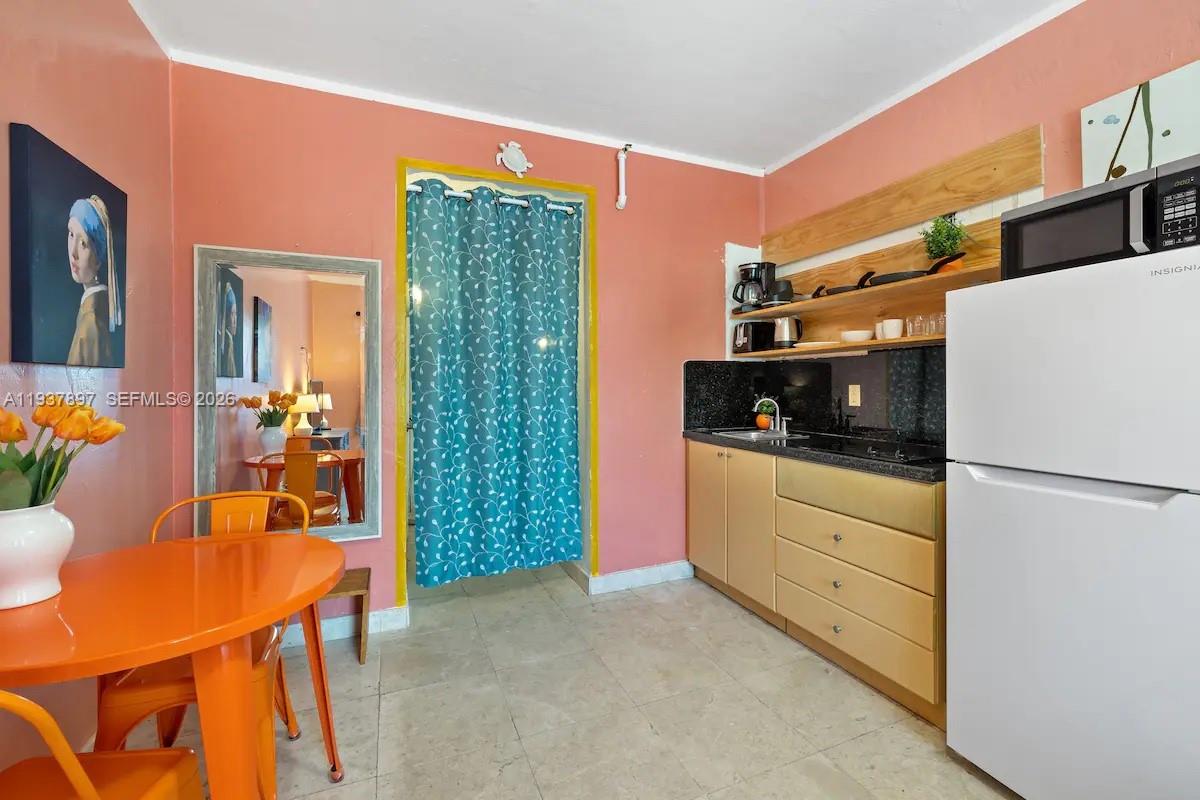 A kitchen with light wood cabinets, a white refrigerator, and an orange dining table — 255 W 24th St # 234, Miami Beach FL 33140, MIAMI BEACH, FL