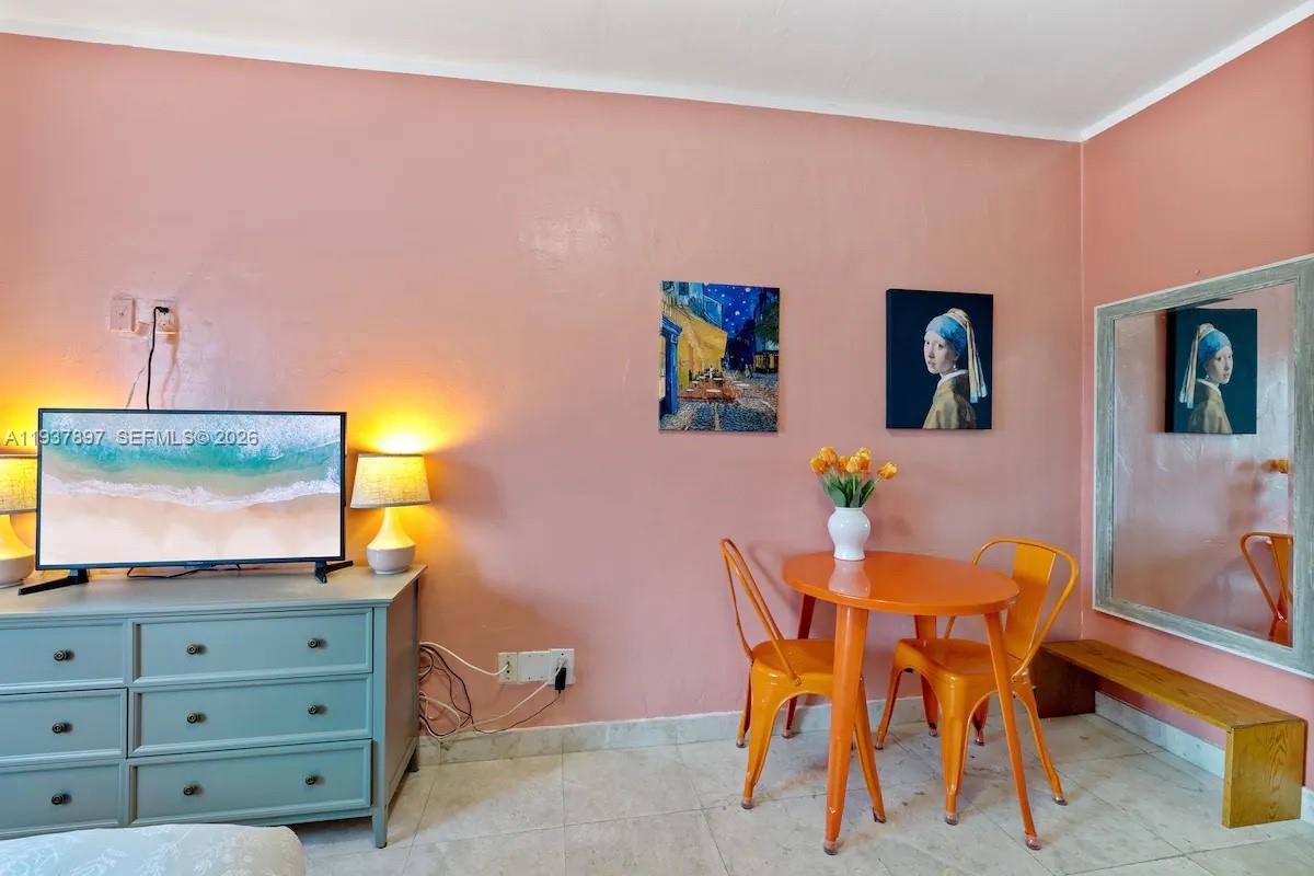 A room with pink walls features a blue dresser, a small orange table, and wall art — 255 W 24th St # 234, Miami Beach FL 33140, MIAMI BEACH, FL
