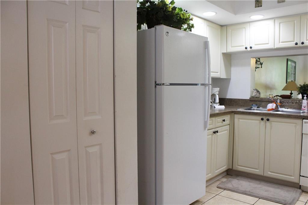 A kitchen features white cabinets, a white refrigerator, and a sink with a pass-through window — 4450 47TH AVENUE W UNIT 102, BRADENTON, FL