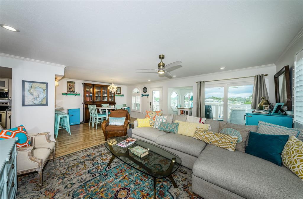 A living room with a gray sectional sofa, a glass coffee table, and dining area — 20019 GULF BOULEVARD UNIT 9, INDIAN ROCKS BEACH, FL