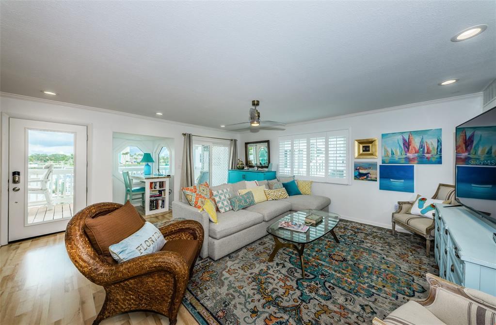 A living room features a sectional sofa, wicker chair, glass coffee table, and coastal decor — 20019 GULF BOULEVARD UNIT 9, INDIAN ROCKS BEACH, FL