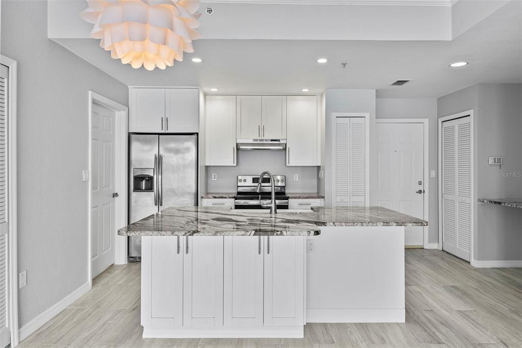A modern kitchen features white cabinetry, stainless steel appliances, and a granite-topped center island — 700 HARBOUR ISLAND UNIT 238, TAMPA, FL