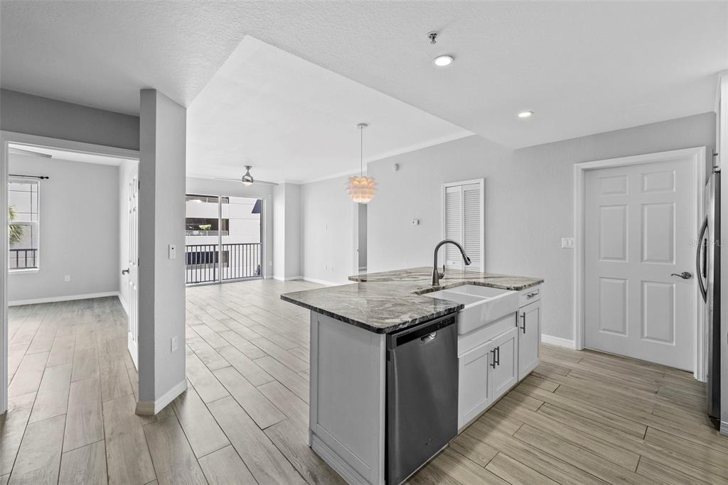 A kitchen island with a farmhouse sink and granite countertop overlooks an open living area — 700 HARBOUR ISLAND UNIT 238, TAMPA, FL