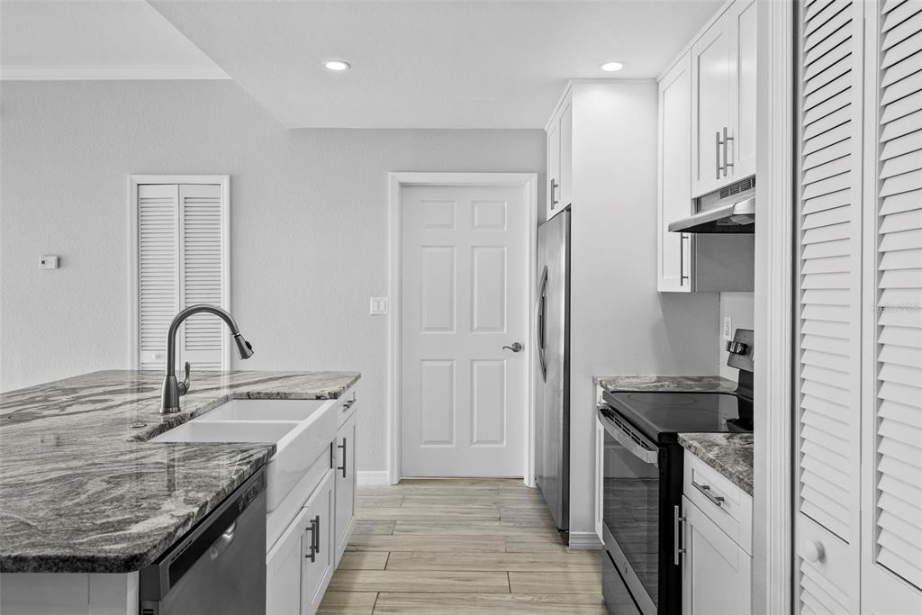 A modern kitchen features a granite-topped island, white cabinetry, stainless steel appliances, and tile flooring — 700 HARBOUR ISLAND UNIT 238, TAMPA, FL