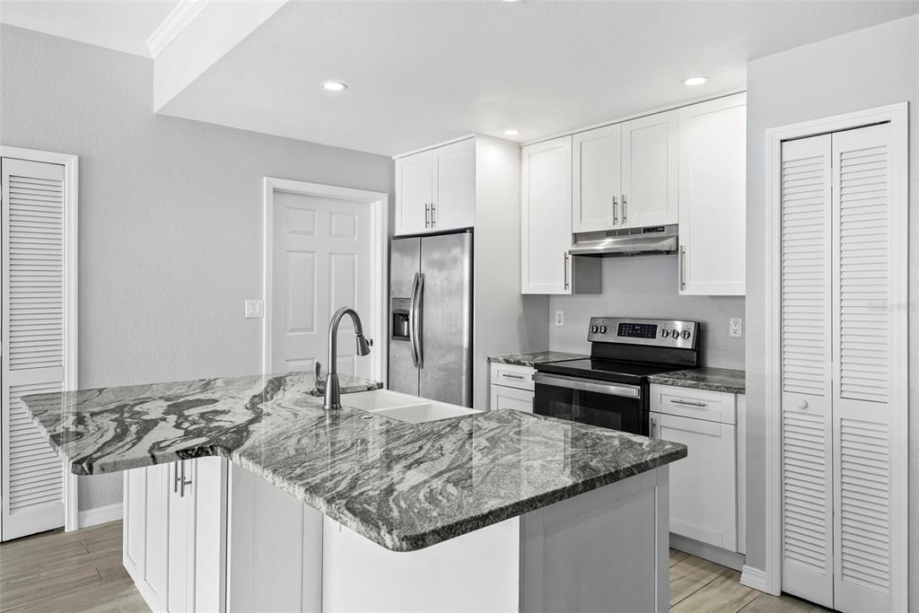 A kitchen features white cabinets, stainless steel appliances, and a large granite-topped island — 700 HARBOUR ISLAND UNIT 238, TAMPA, FL