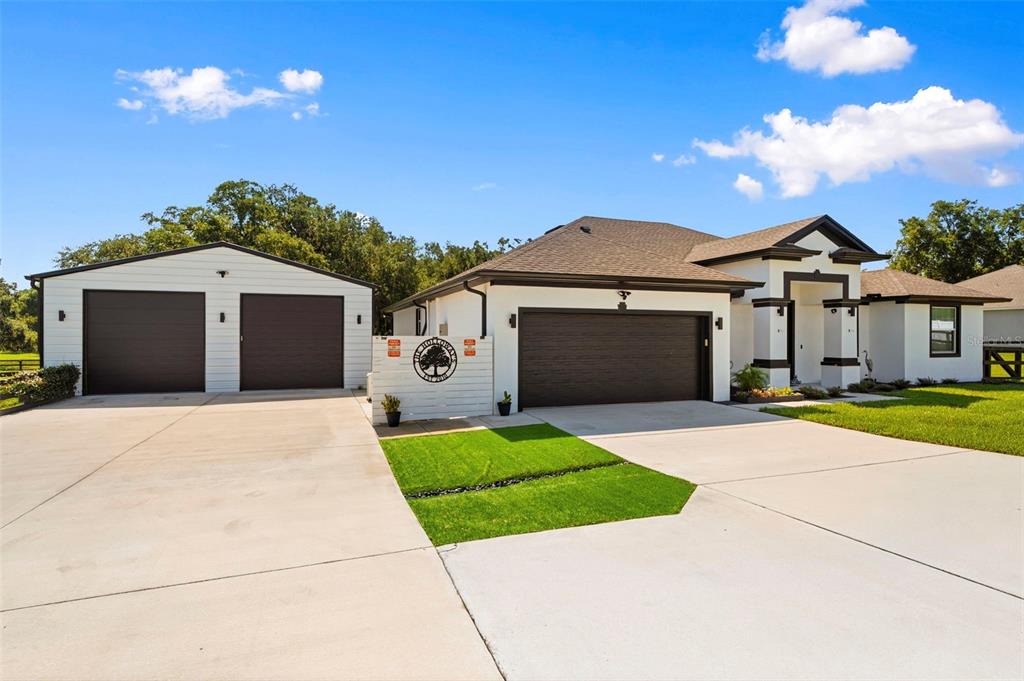 A white house with a detached garage and a large concrete driveway under a blue sky — 437 GANDY CEMETERY ROAD, BARTOW, FL