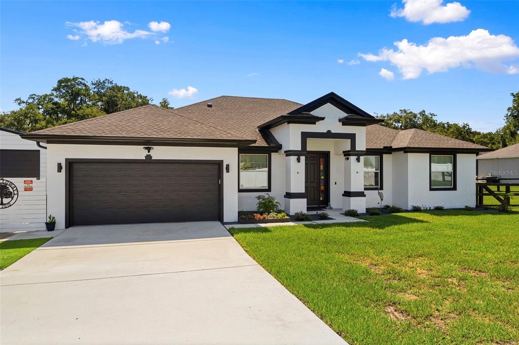 A single-story house with white stucco walls, a dark garage door, and a dark roof — 437 GANDY CEMETERY ROAD, BARTOW, FL