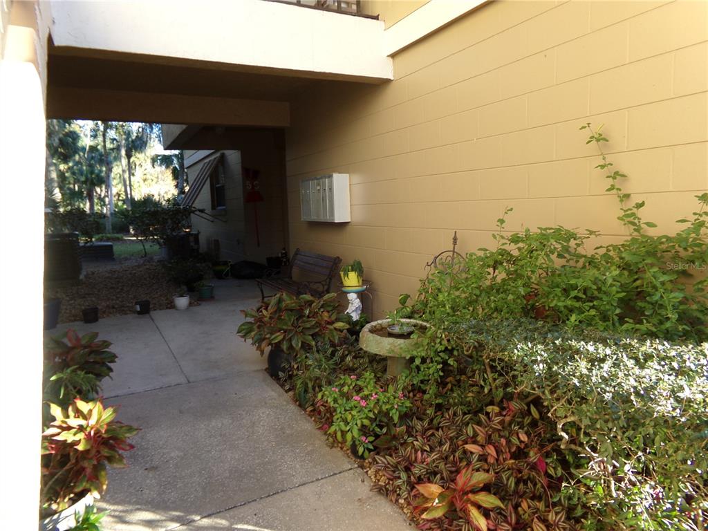 A concrete walkway leads to a covered entrance with a bench and a small fountain — 110 CYPRESS WOODS CT UNIT 5C, DELTONA, FL