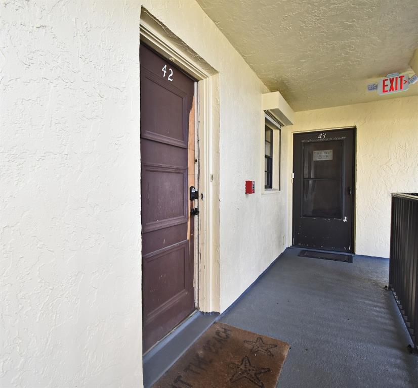 An outdoor corridor shows two apartment doors numbered 42 and 43 with an exit sign — 4570 OCEAN BEACH BOULEVARD UNIT 42, COCOA BEACH, FL