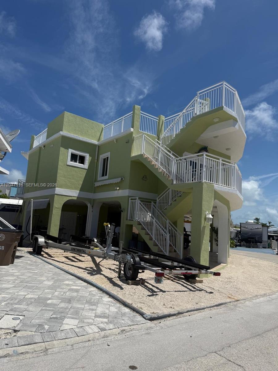 A light green, multi-story house features an exterior staircase and a boat trailer parked underneath — 65821 Overseas Hwy 176, Long Key FL 33001, LONG KEY, FL