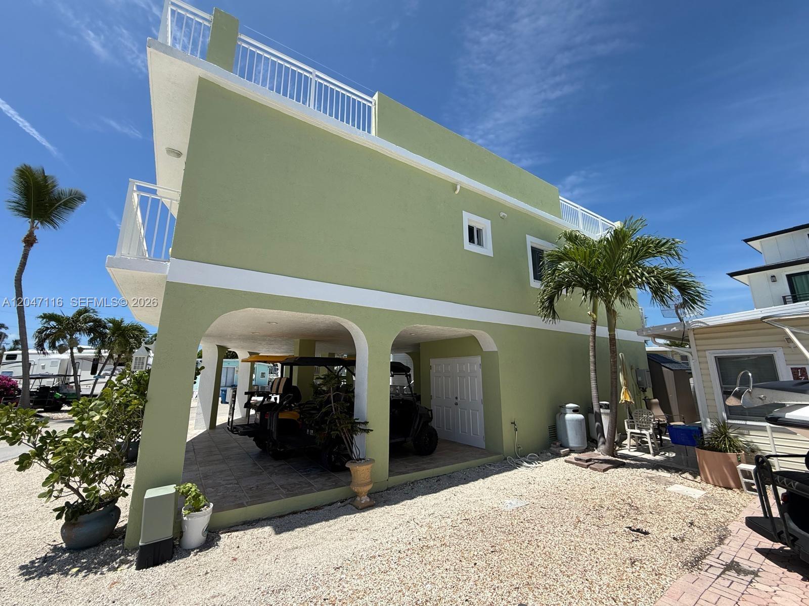 A light green two-story house features a covered ground-level parking area and a rooftop deck — 65821 Overseas Hwy 176, Long Key FL 33001, LONG KEY, FL