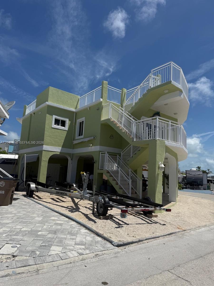 A light green, elevated multi-story house features exterior staircases and a boat trailer parked underneath — 65821 Overseas Hwy 176, Long Key FL 33001, LONG KEY, FL
