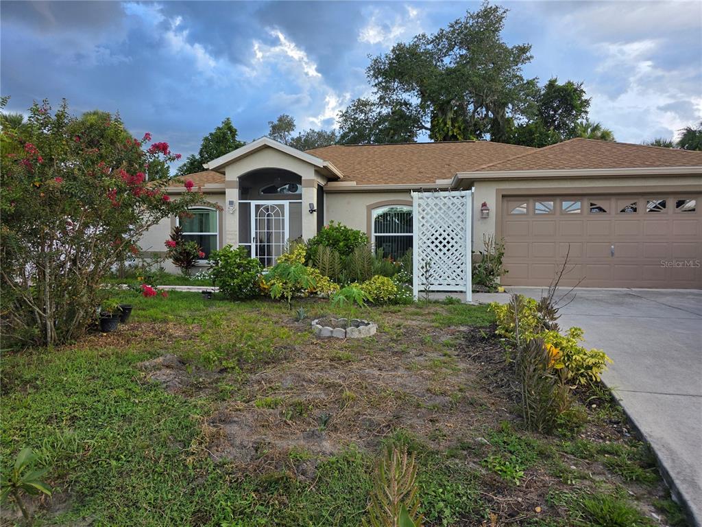 A single-story house with a tan stucco exterior, a brown shingled roof, and a garage — 4943 BECKHAM COURT, NORTH PORT, FL