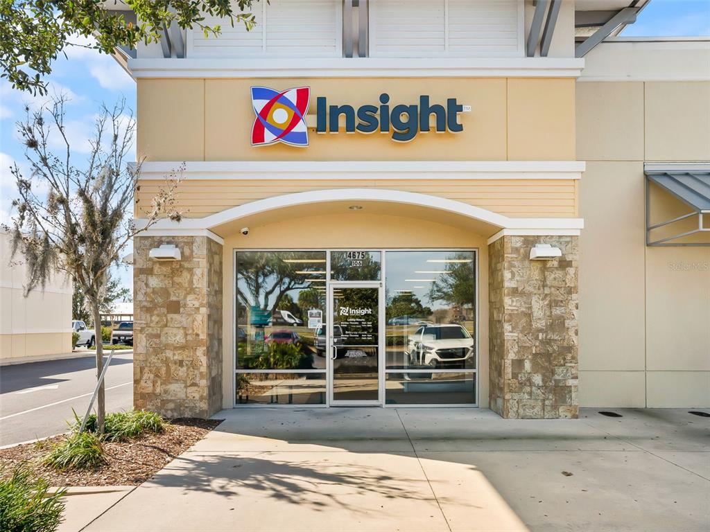 The exterior of a commercial building features a tan facade, stone accents, and glass doors — 4675 E SR 44 DRIVE UNIT 106, WILDWOOD, FL