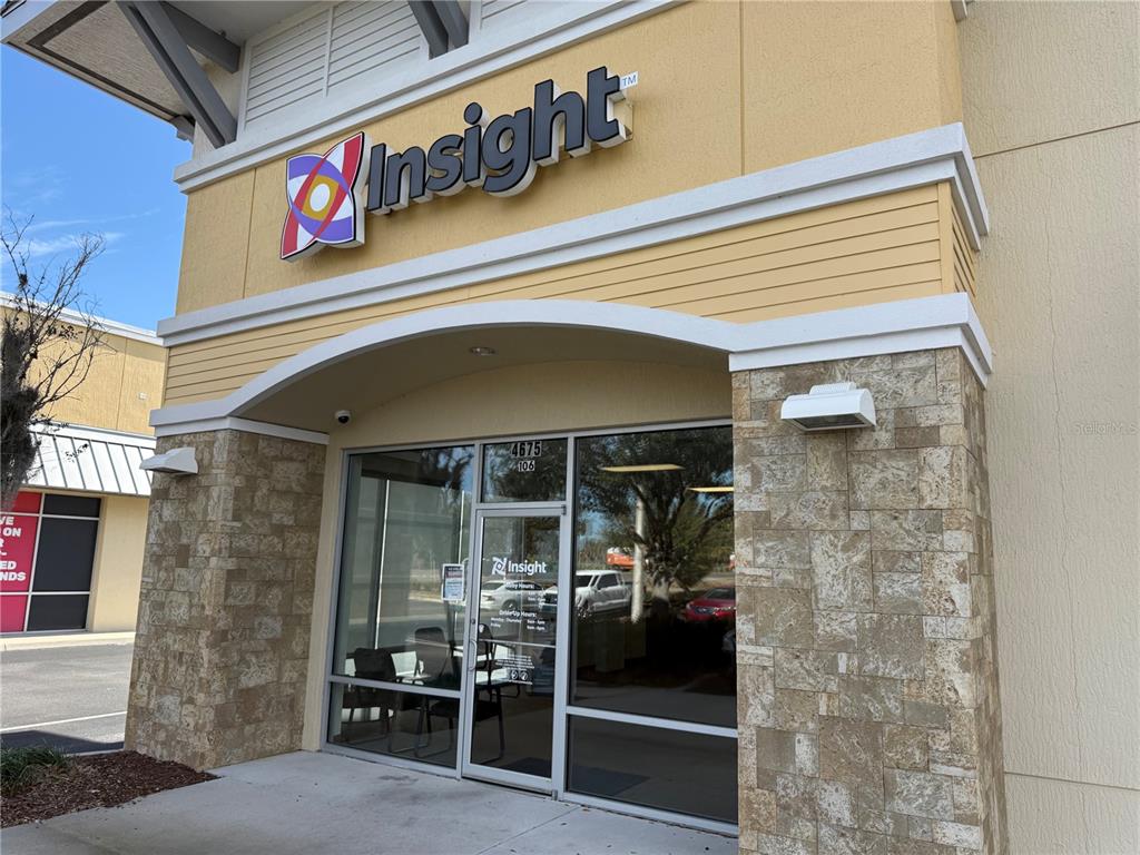The exterior entrance of a commercial building features a stone facade and a glass door — 4675 E SR 44 DRIVE UNIT 106, WILDWOOD, FL