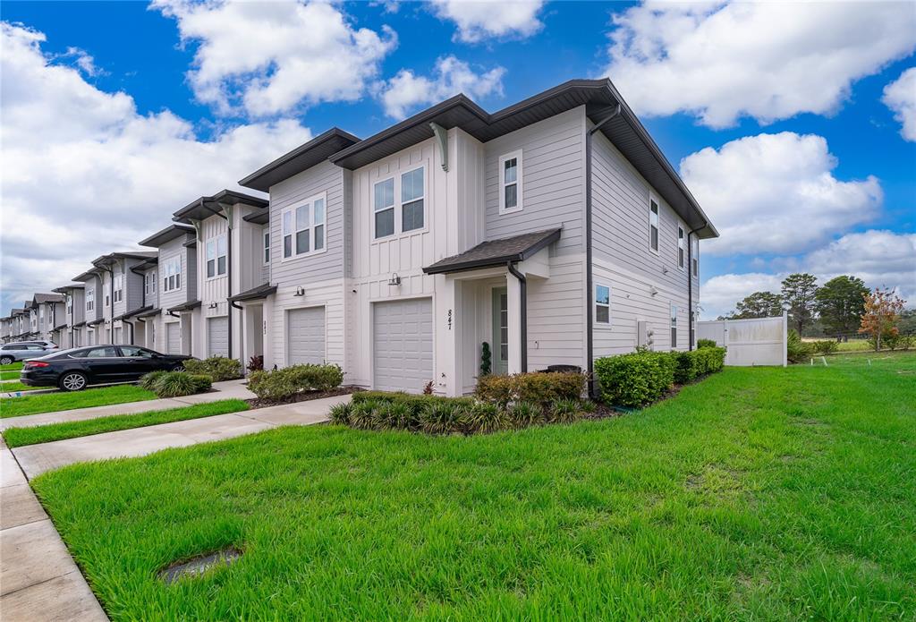 A row of modern two-story townhouses features gray and white siding with attached garages — 847 LONGBOAT DRIVE, DAVENPORT, FL