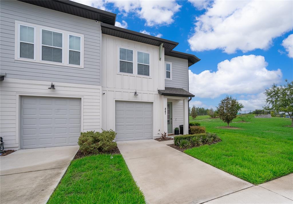 A two-story townhouse with gray and white siding, two garage doors, and a grassy yard — 847 LONGBOAT DRIVE, DAVENPORT, FL
