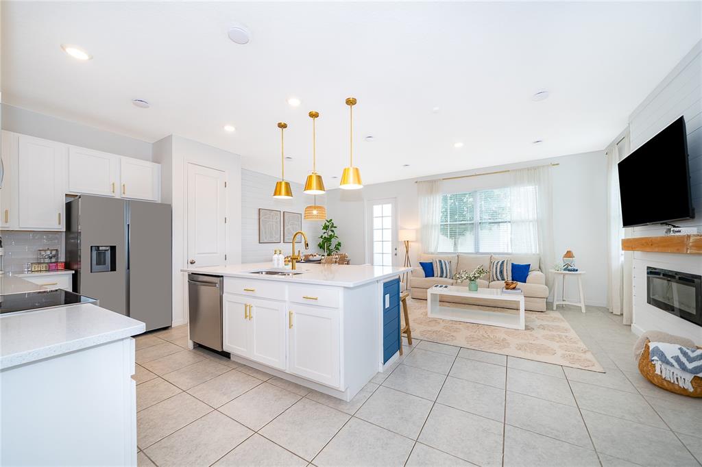 A bright open-concept kitchen and living area featuring white cabinetry, a central island, and tile flooring — 847 LONGBOAT DRIVE, DAVENPORT, FL