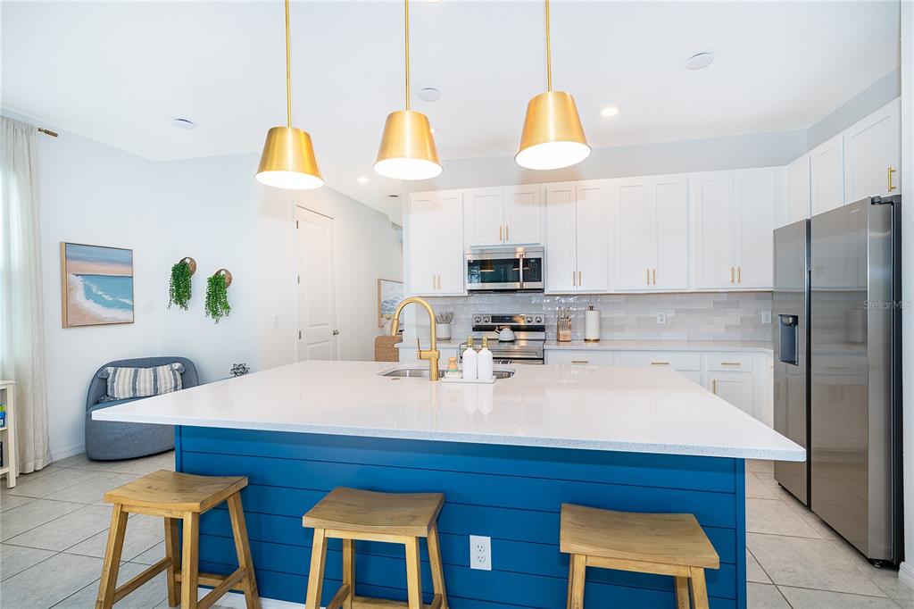 A kitchen features white cabinets, stainless steel appliances, and a blue island with bar stools — 847 LONGBOAT DRIVE, DAVENPORT, FL