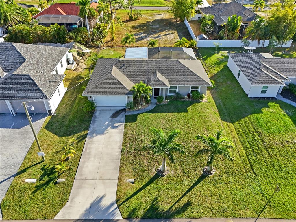 An aerial view shows a single-story house with a driveway, palm trees, and a pool cage — 2714 NW 22ND TERRACE, CAPE CORAL, FL