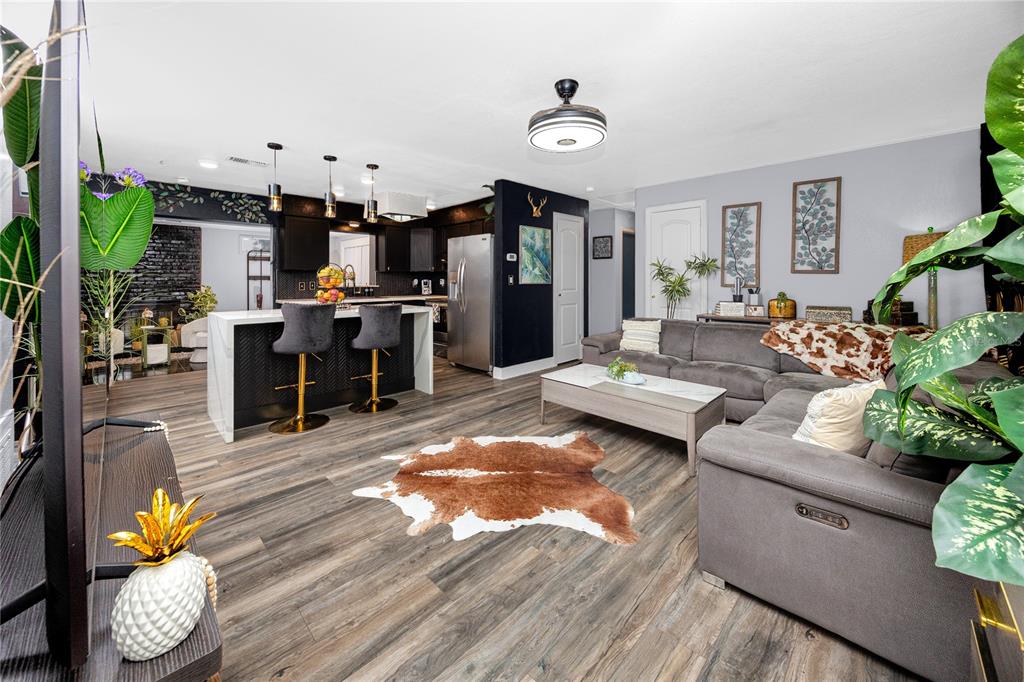 An open-concept living room and kitchen featuring wood-look flooring, a grey sectional, and a kitchen island — 6200 52ND AVENUE N, ST PETERSBURG, FL