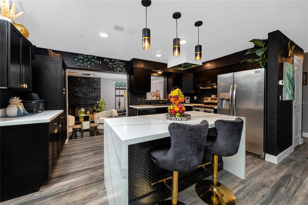 A modern kitchen features black cabinetry, a white marble island, and three pendant lights — 6200 52ND AVENUE N, ST PETERSBURG, FL