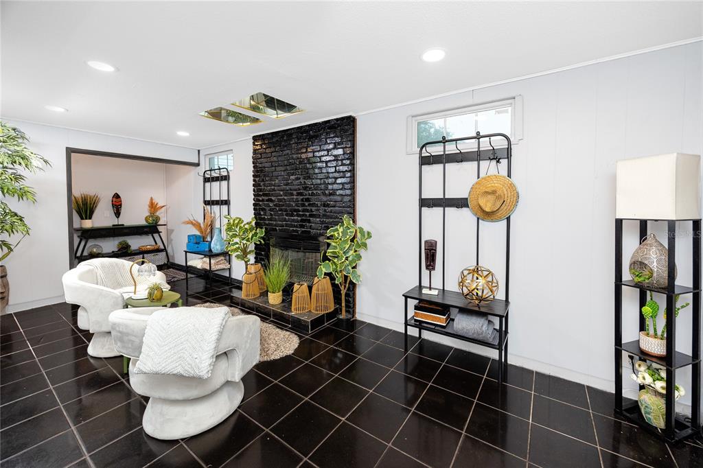 A living room features a black brick fireplace, glossy black tile floors, and white chairs — 6200 52ND AVENUE N, ST PETERSBURG, FL