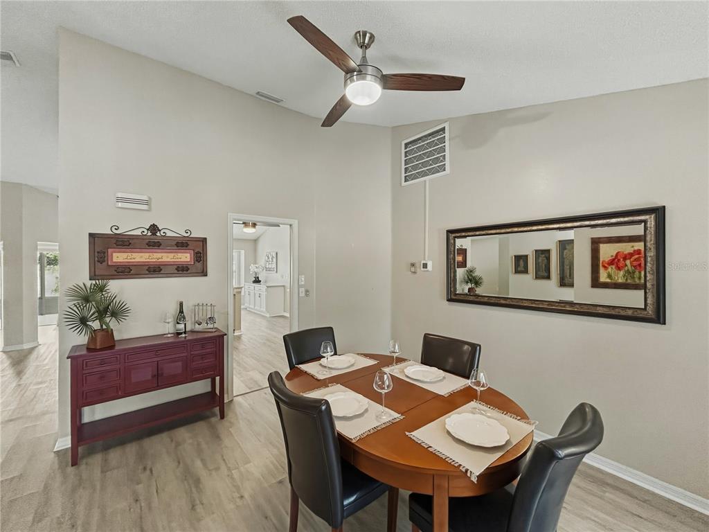 A dining room features a wooden table, four chairs, a sideboard, and a large wall mirror — 2309 E DEL WEBB BOULEVARD, SUN CITY CENTER, FL