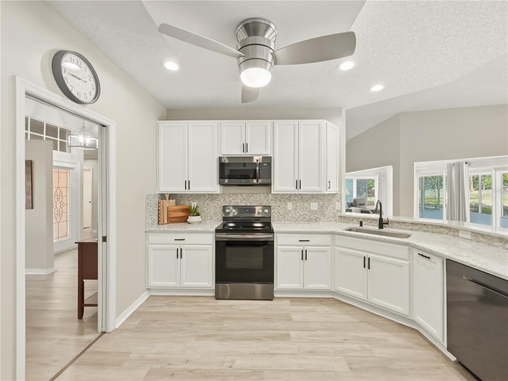 A kitchen with white cabinets, stainless steel appliances, and light wood-look flooring — 2309 E DEL WEBB BOULEVARD, SUN CITY CENTER, FL