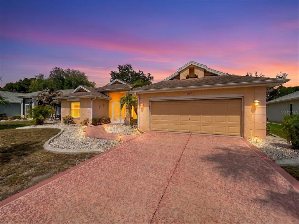 A single-story house with a tan stucco exterior, a two-car garage, and a paved driveway — 2309 E DEL WEBB BOULEVARD, SUN CITY CENTER, FL