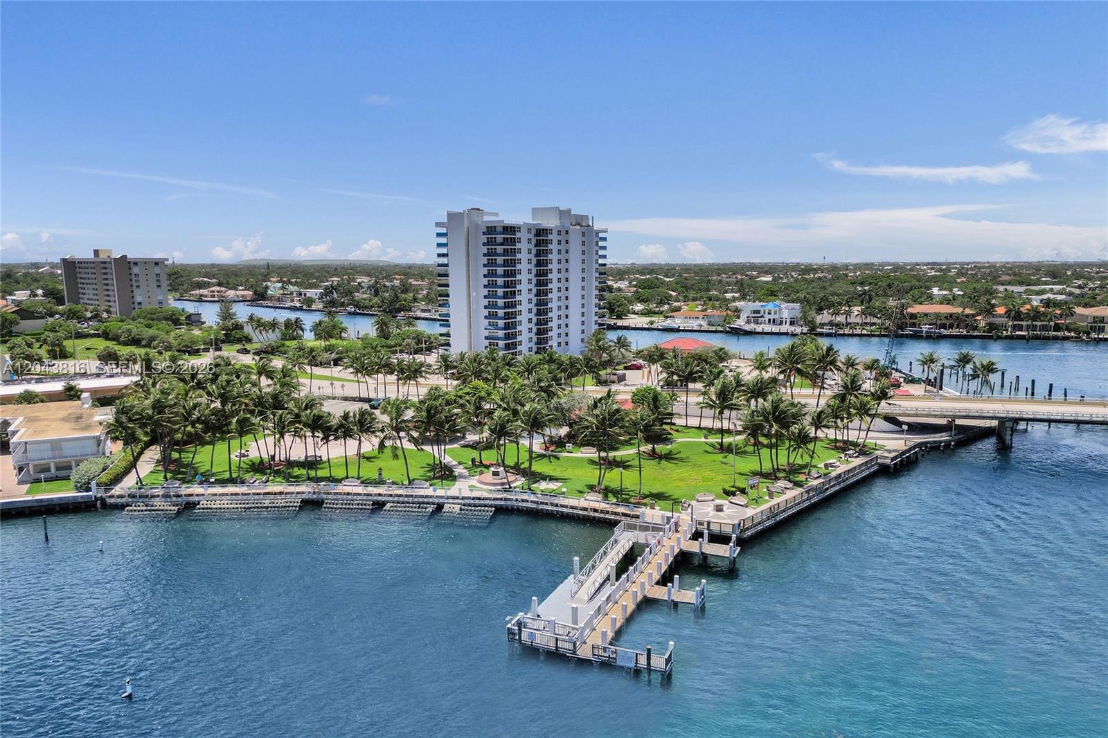 An aerial view shows a waterfront park with a pier, palm trees, and high-rise buildings — 2639 N Riverside Dr # 206, Pompano Beach FL 33062, POMPANO BEACH, FL