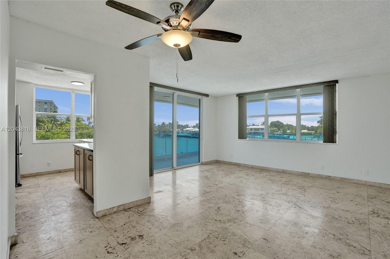 An open living area features a ceiling fan, tile flooring, and large windows overlooking water — 2639 N Riverside Dr # 206, Pompano Beach FL 33062, POMPANO BEACH, FL