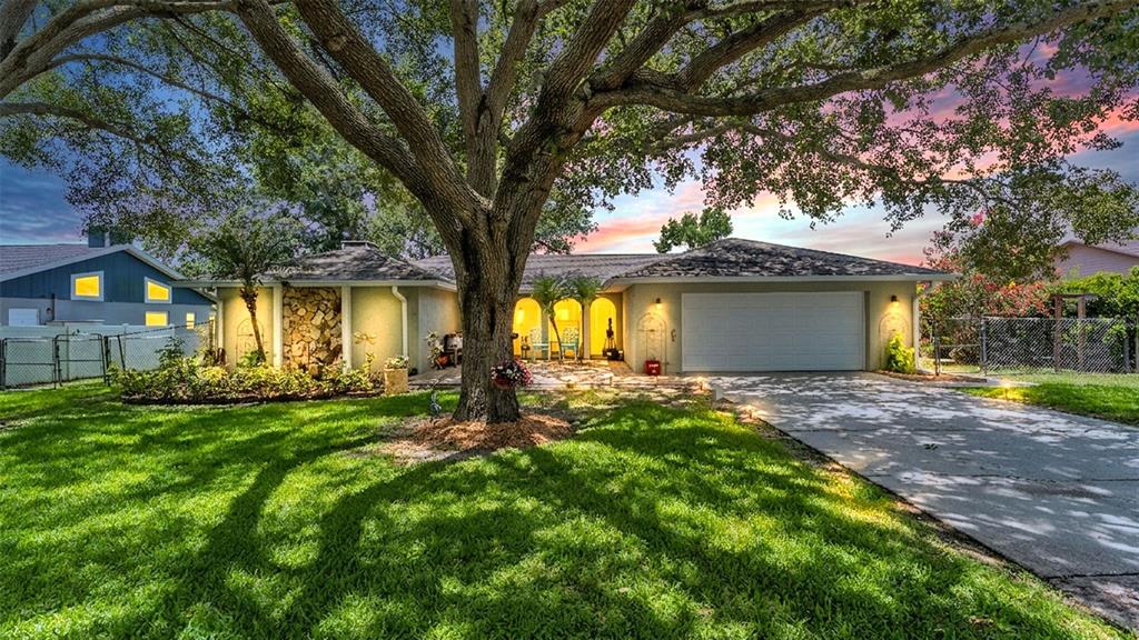 A single-story house with a large oak tree, stone accent wall, and attached garage — 422 WILLOW RUN, LAKELAND, FL