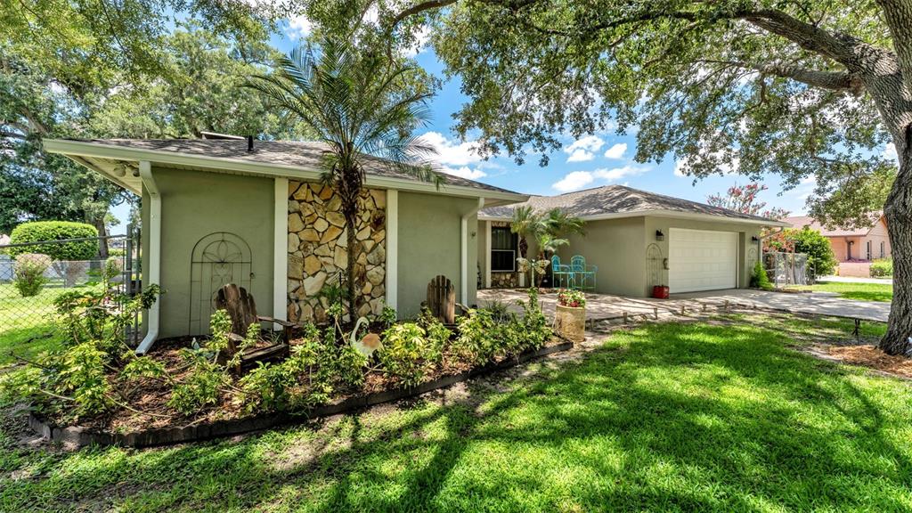 A single-story house with a stone accent wall, palm tree, and attached garage — 422 WILLOW RUN, LAKELAND, FL