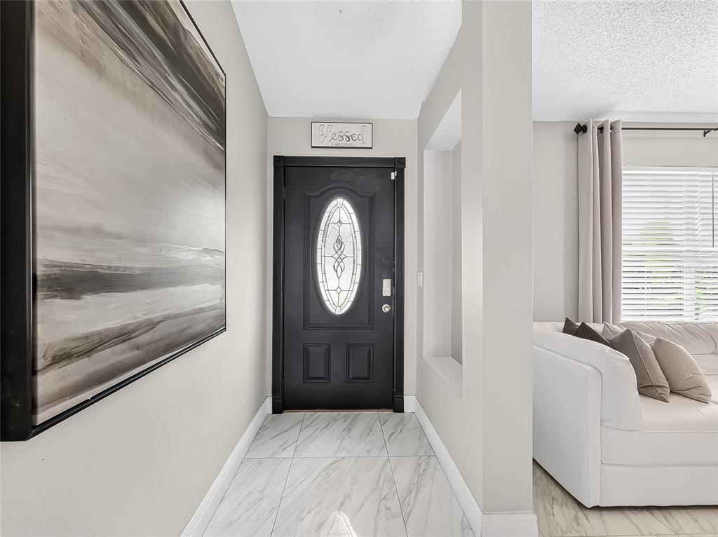 An entryway features a black front door, marble-look tile flooring, and a large abstract painting — 5014 SAWDUST CIRCLE, OCOEE, FL