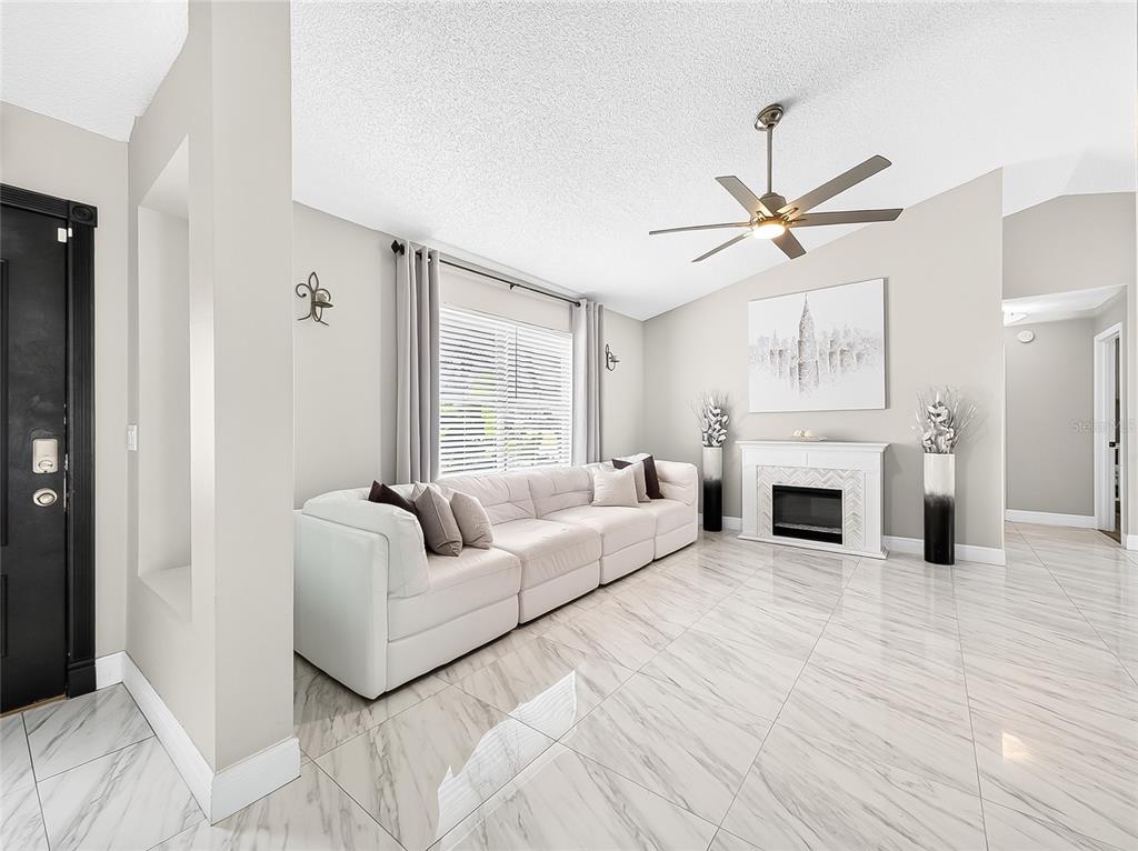 A living room features a white sectional sofa, a fireplace, and light-colored marble tile flooring — 5014 SAWDUST CIRCLE, OCOEE, FL