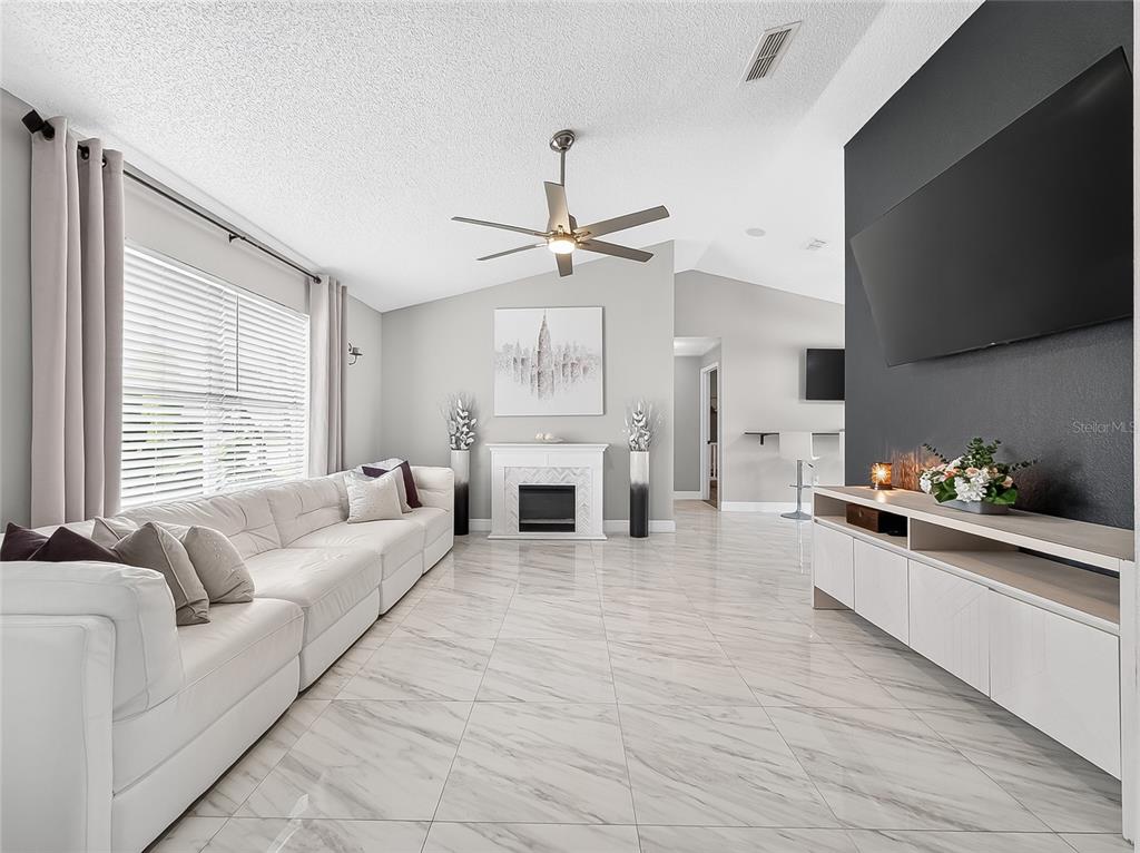 A living room features white tile floors, a white sofa, a fireplace, and a wall-mounted television — 5014 SAWDUST CIRCLE, OCOEE, FL