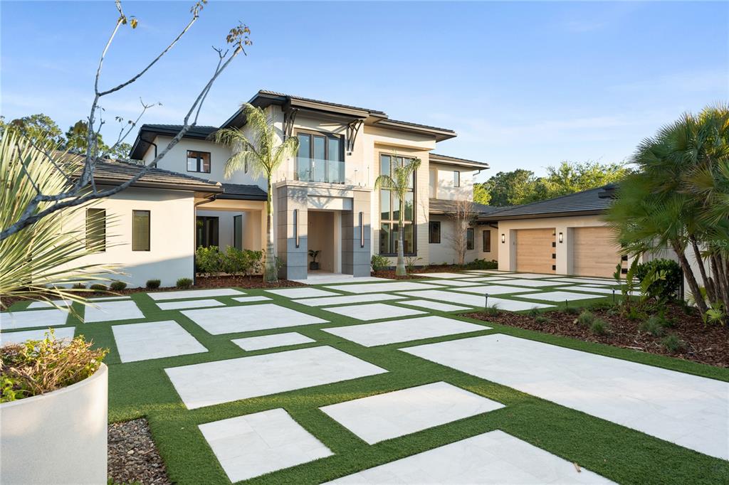 A modern two-story house features a large paver driveway with integrated artificial turf sections — 8506 LAKE NONA SHORE DR, ORLANDO, FL