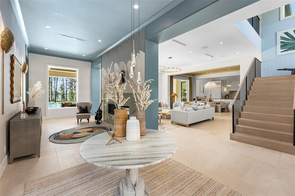 A spacious foyer with a marble table leads to an open-concept living area and staircase — 8506 LAKE NONA SHORE DR, ORLANDO, FL