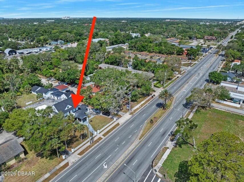 An aerial view shows a house with a dark roof situated beside a multi-lane road — 934 S RIDGEWOOD AVENUE, DAYTONA BEACH, FL
