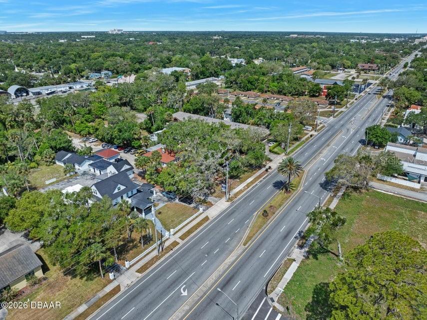 An aerial view shows a multi-building property with dark roofs situated beside a multi-lane road — 934 S RIDGEWOOD AVENUE, DAYTONA BEACH, FL